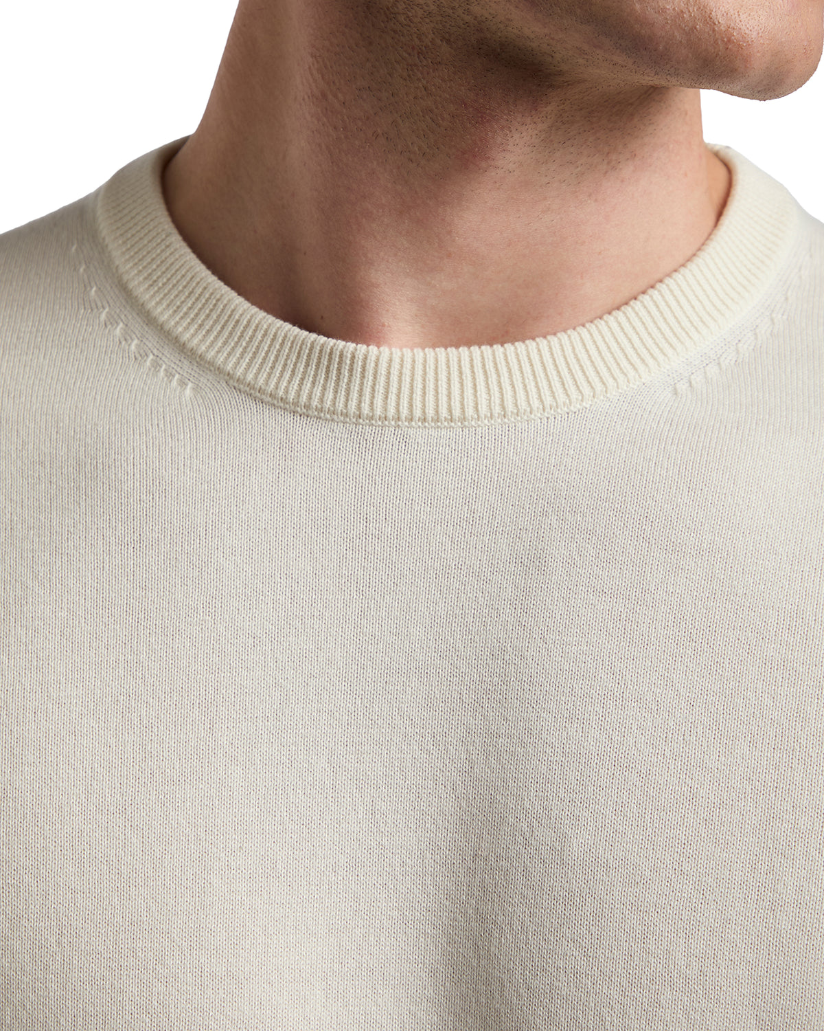 Cream-colored knitted sweater with a classic crew neckline and subtle stitching details.