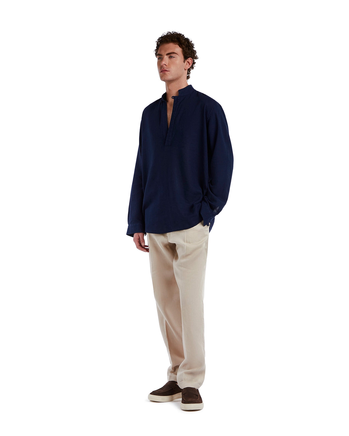 Navy blue linen shirt with half-button placket, paired with beige trousers and brown slip-on shoes.