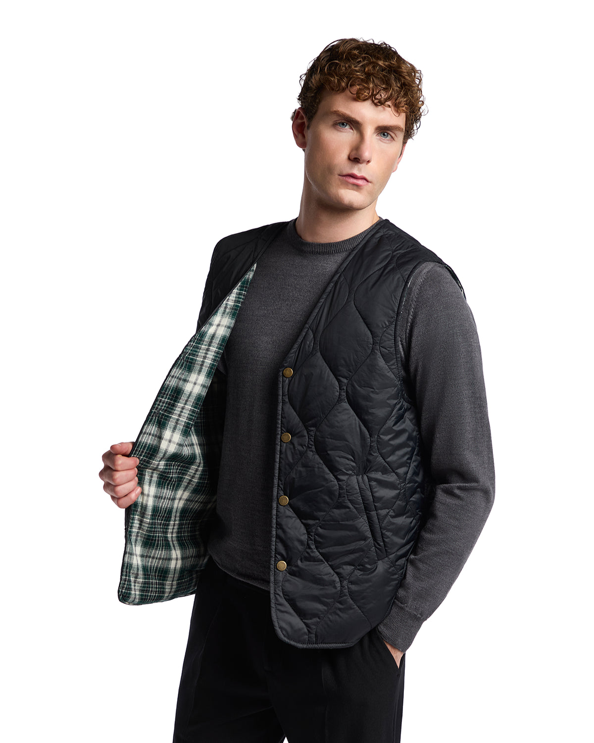 Men's black quilted vest with green plaid lining, perfect for layering in cool weather.