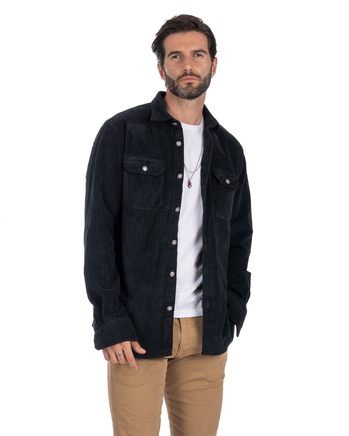 Men's black corduroy button-up shirt jacket with silver snap buttons, chest pockets, worn over white tee and tan pants.