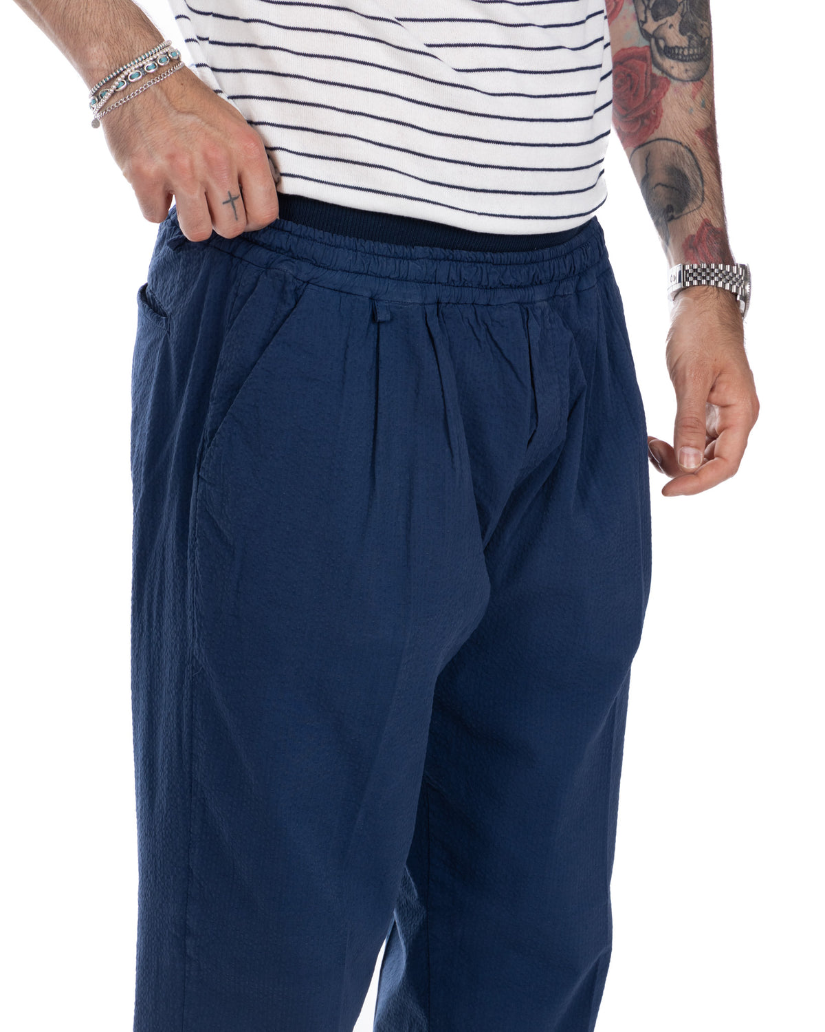 Navy blue relaxed fit pleated trousers with elastic waistband, textured fabric, and side pockets.