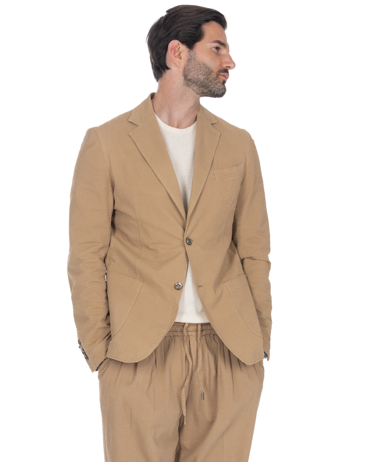 Beige textured cotton blazer with notched lapels, paired with matching drawstring trousers and white knit tee.