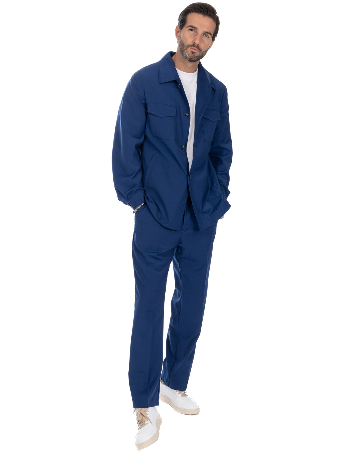 Navy blue men's suit with button-up shirt jacket, straight-leg trousers, and white sneakers. Casual formal wear.