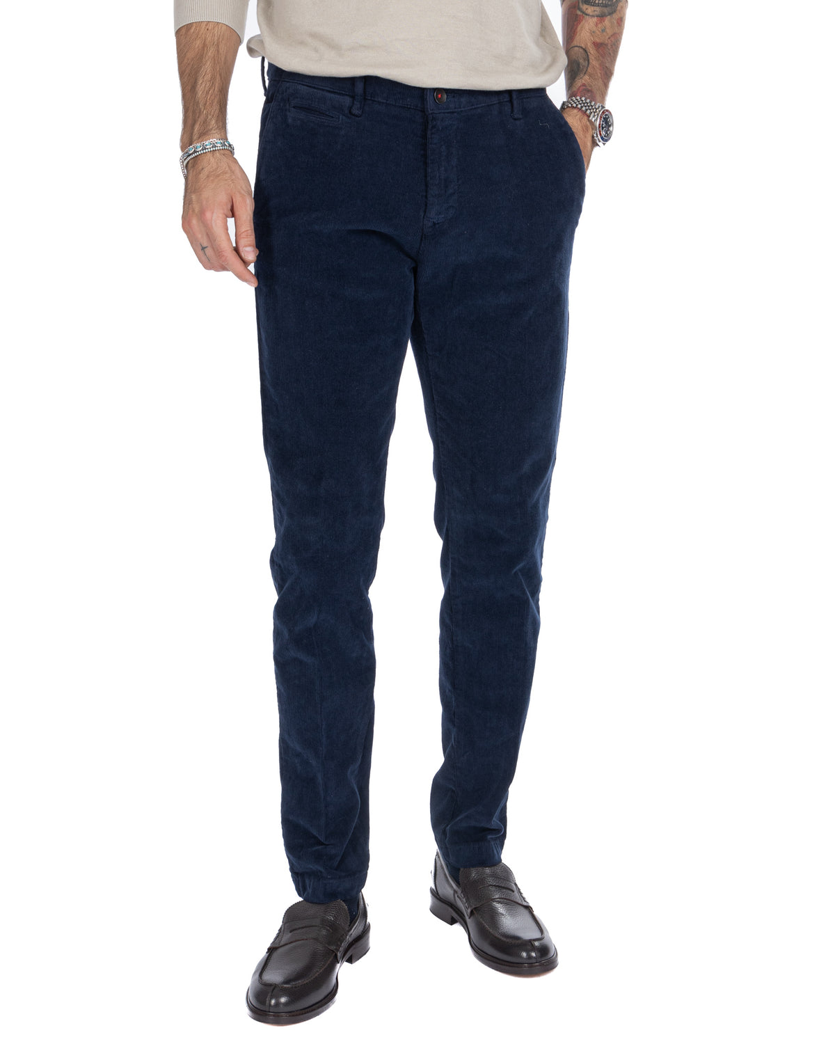 Men's navy blue corduroy slim-fit pants with elastic cuffs, paired with black leather loafers.