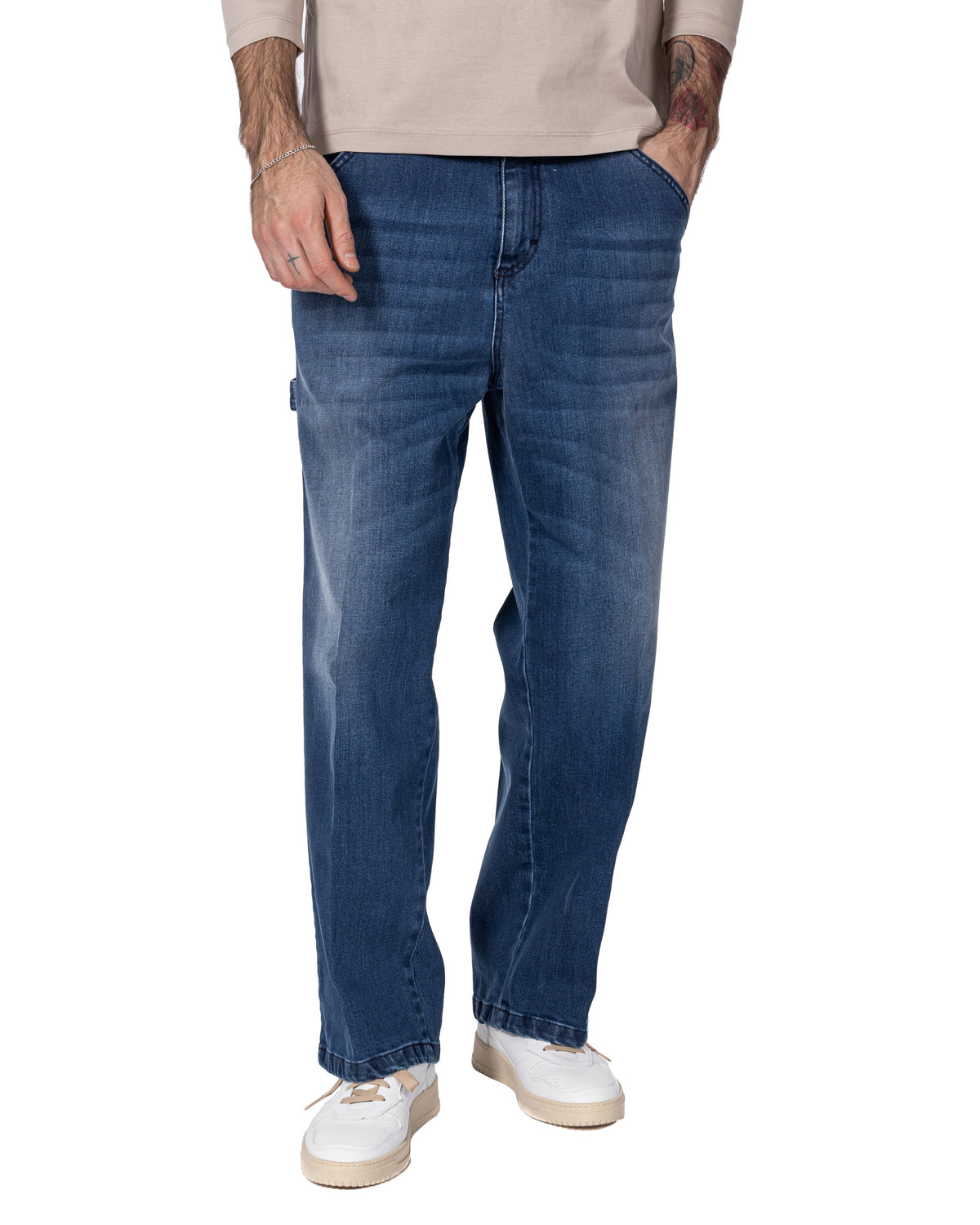 Men's dark blue straight-leg denim jeans with faded wash, paired with white sneakers and beige top.