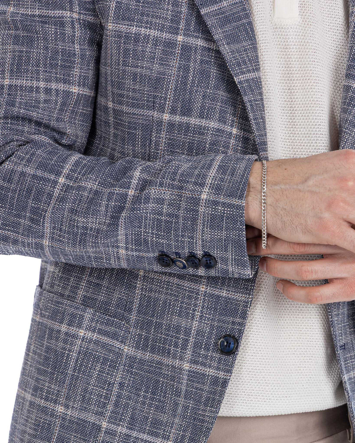 Navy blue windowpane check wool blazer with gold chain bracelet, white shirt, and dark buttons.