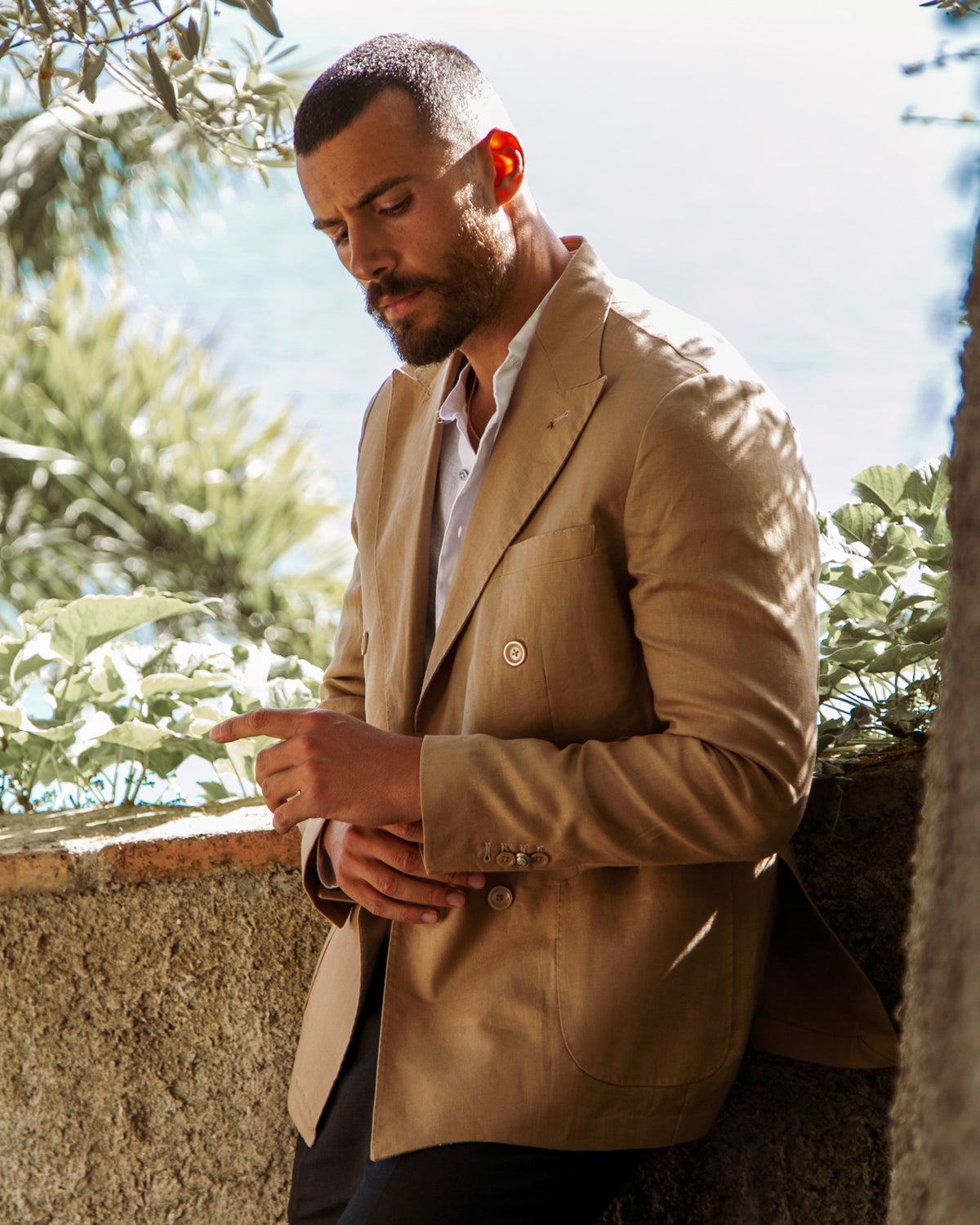 Tan cotton double-breasted blazer with notched lapels, paired with white shirt and dark trousers.