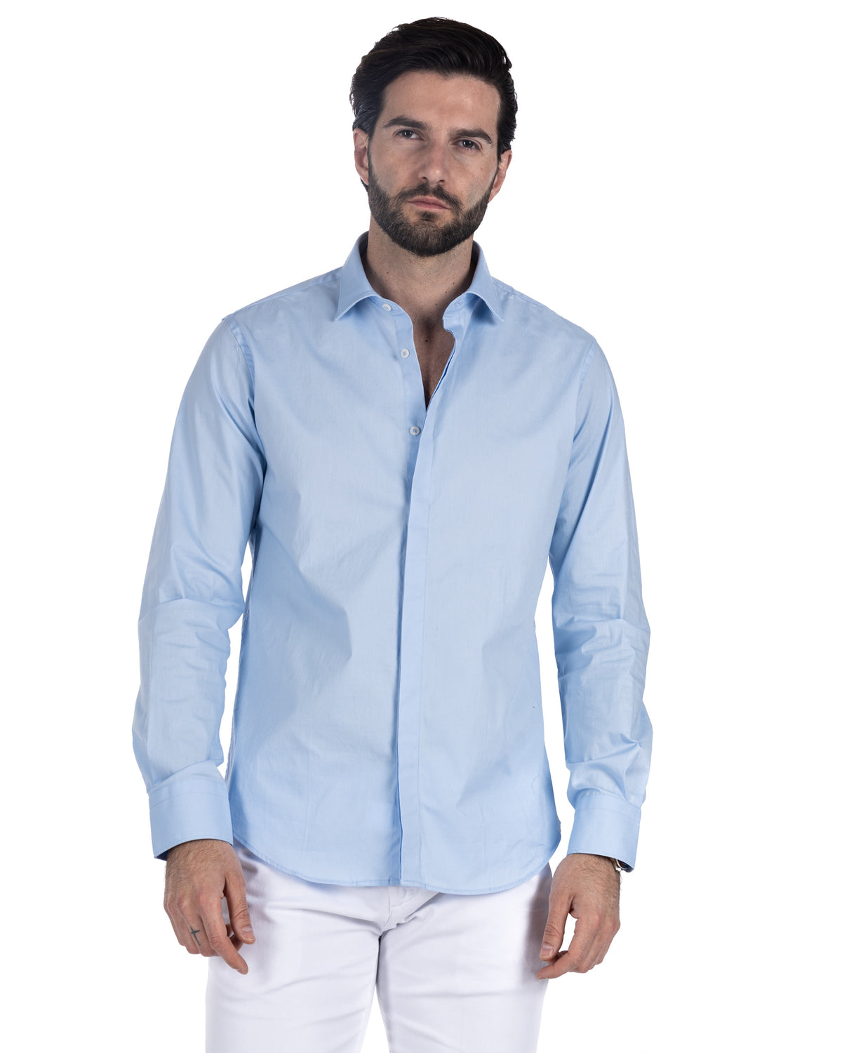 Men's light blue cotton poplin dress shirt with spread collar, worn untucked with white trousers, front view