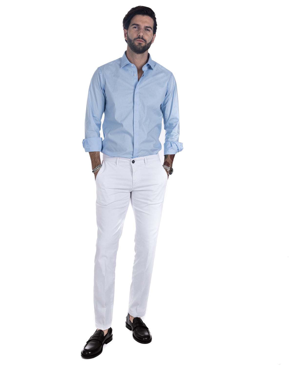 Men's light blue cotton shirt worn over white chino trousers with black loafers, full-length front view
