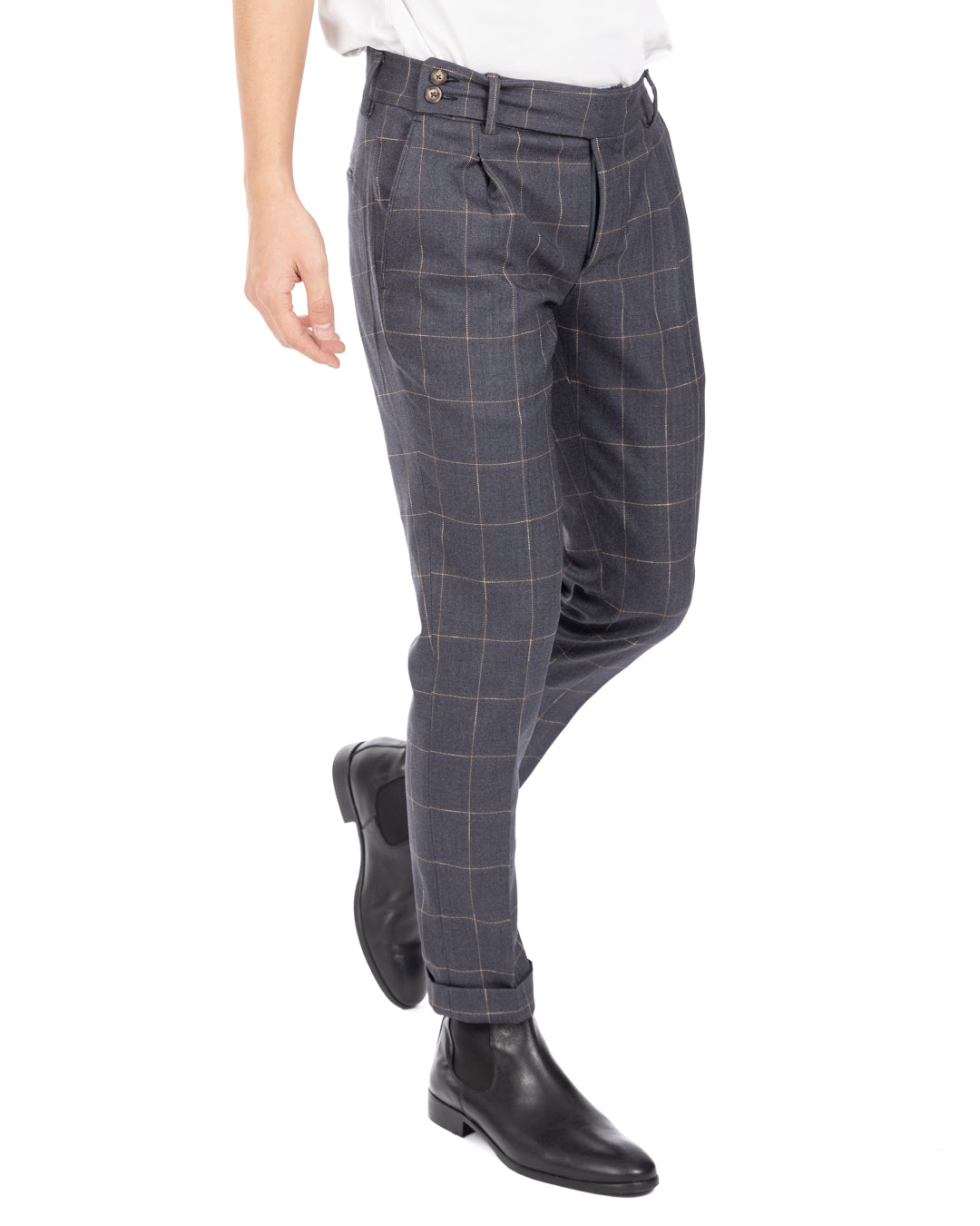 Side view of men's blue-gray windowpane check pleated wool trousers worn with a white t-shirt and black leather boots