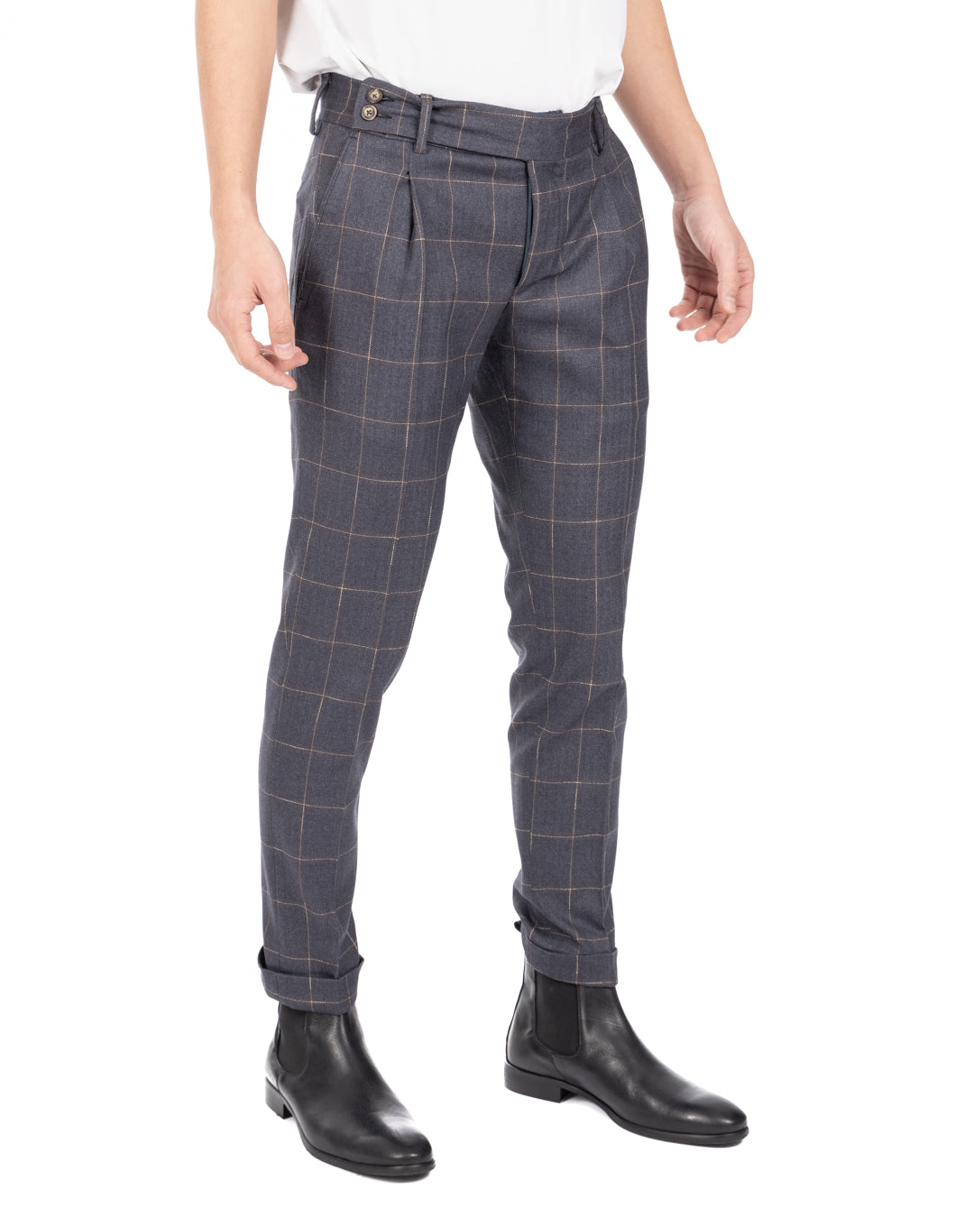 Side view of men's blue-gray windowpane check pleated wool trousers with cuffed hems and black leather Chelsea boots