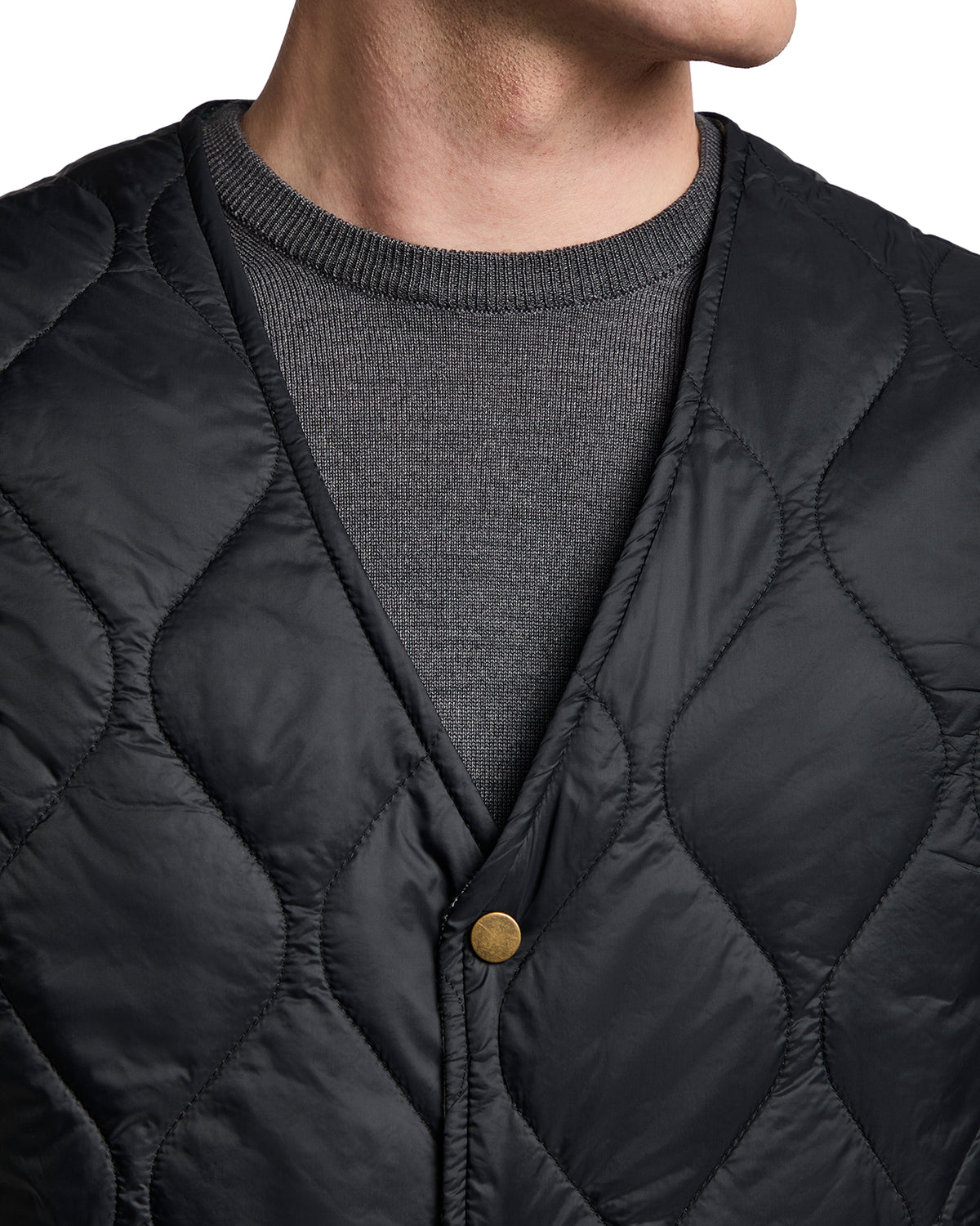 Men's black quilted vest with a button closure, layered over a gray sweater, perfect for casual or outdoor wear.
