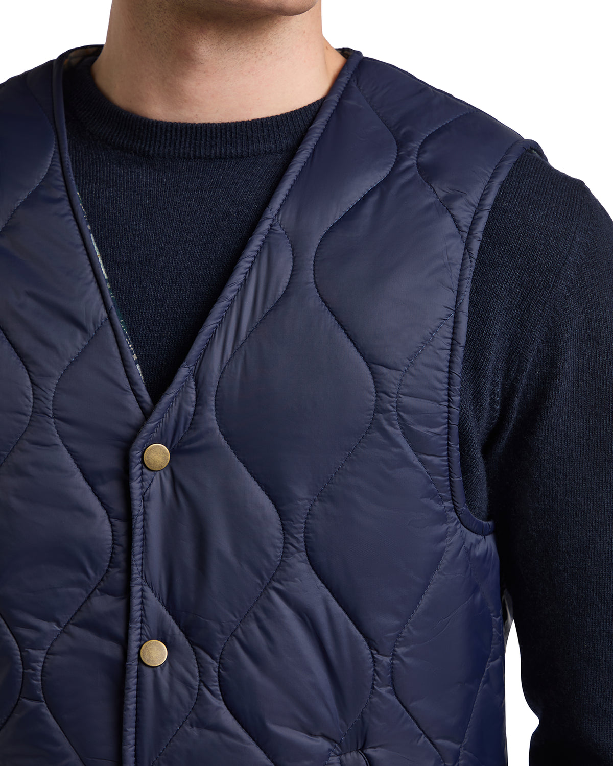 Navy blue quilted vest with gold buttons, perfect for layering in cool weather.