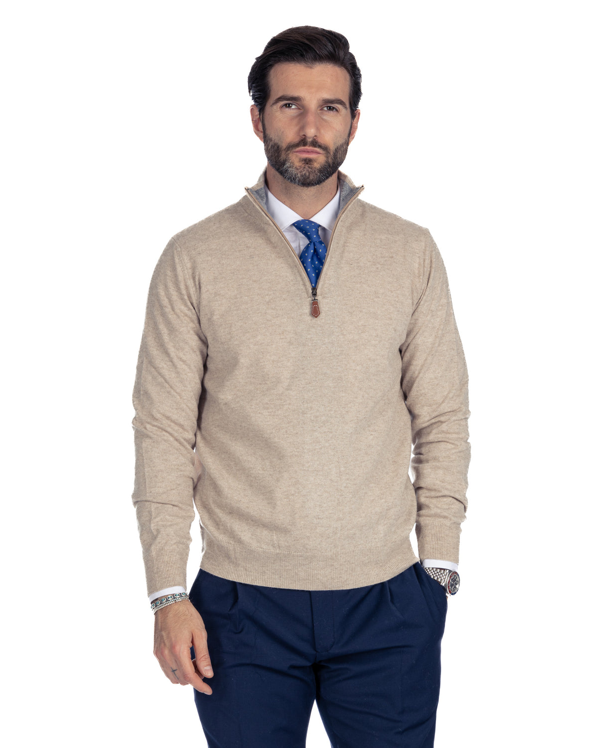 Beige cashmere quarter-zip sweater with leather pull, paired with navy trousers and blue polka dot tie.