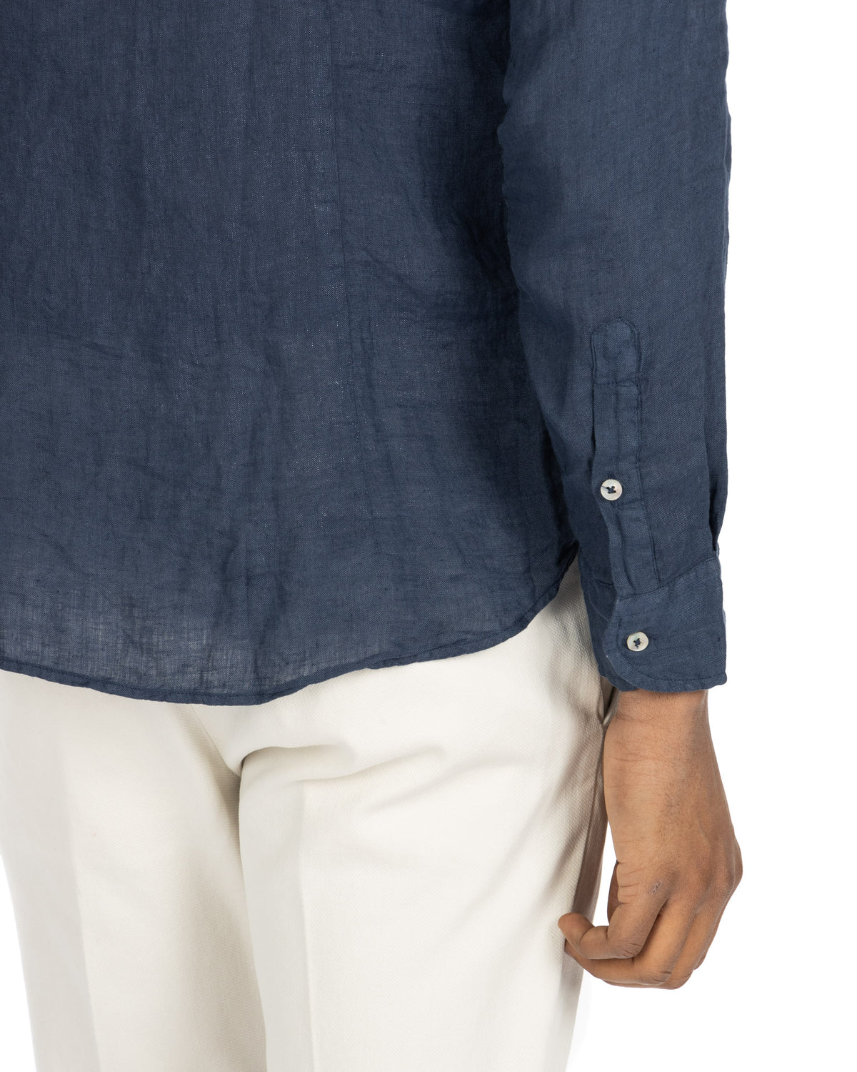 Navy blue linen button-down shirt with long sleeves and white buttons, paired with white trousers.