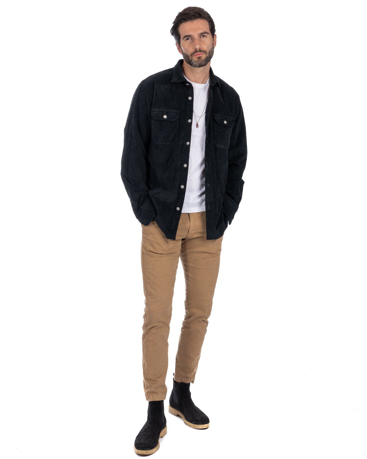 Men's black corduroy overshirt with silver buttons, paired with tan chinos and black suede Chelsea boots.