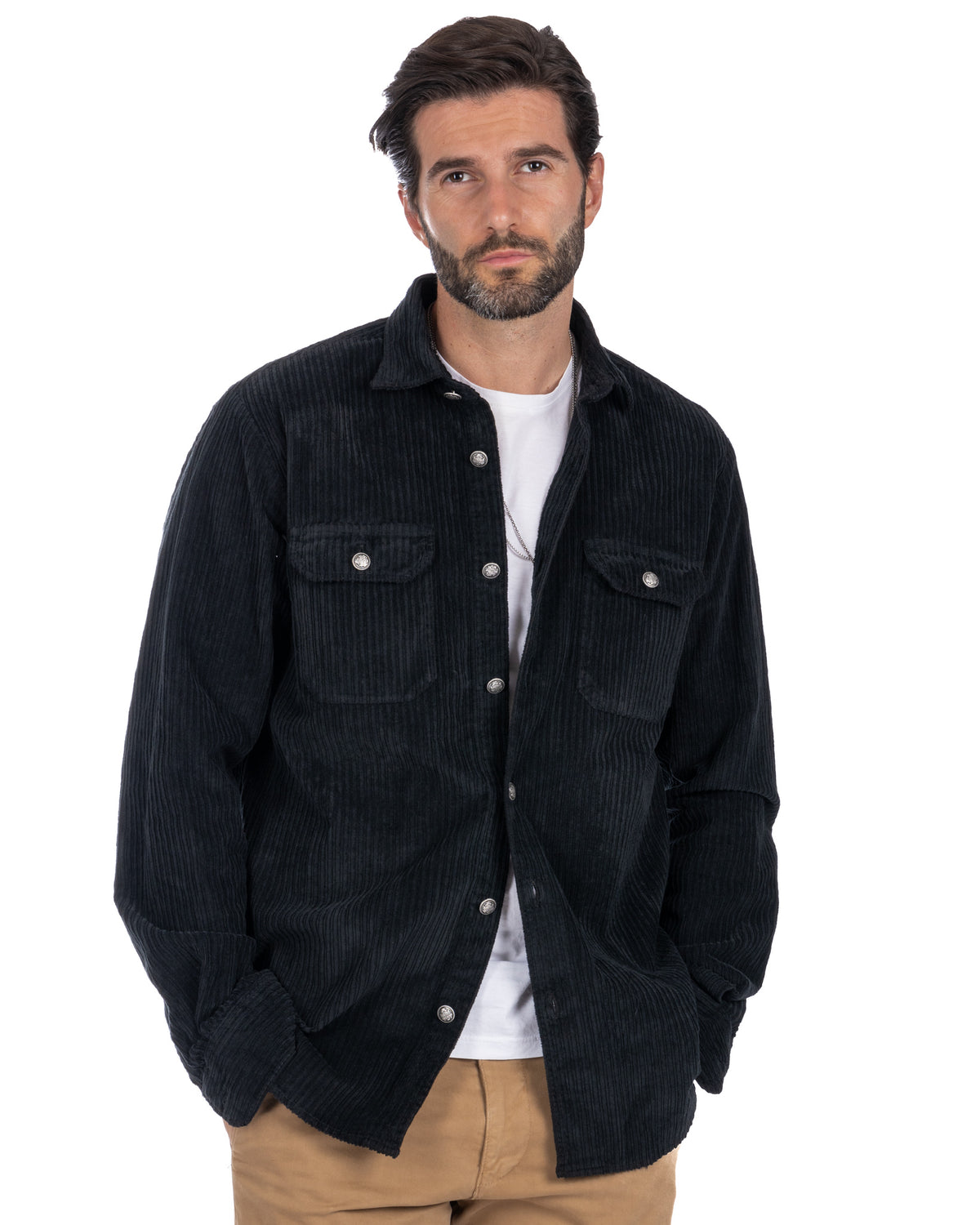 Men's black corduroy button-up shirt jacket with chest pockets, worn over white tee and tan pants.