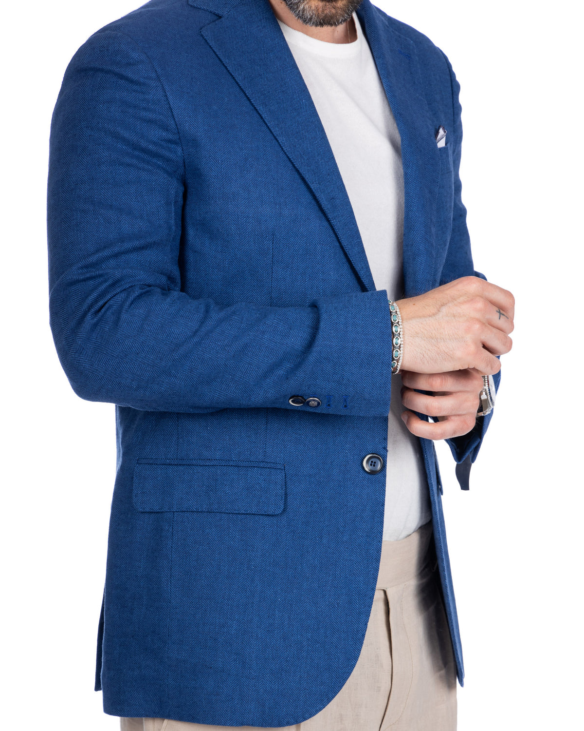 Royal blue herringbone wool blazer with notched lapels, paired with white tee and beige trousers.