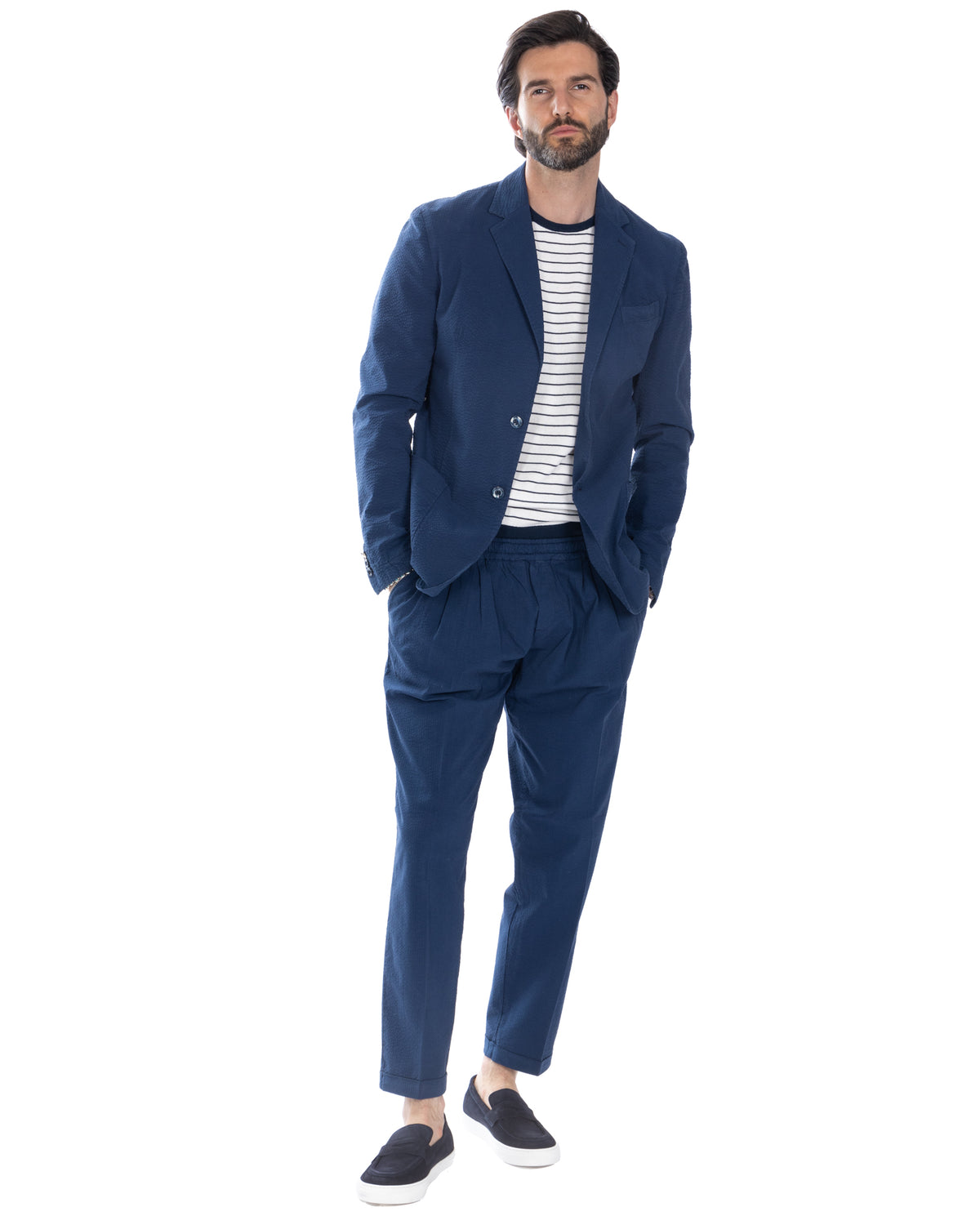 Navy blue textured linen suit with striped tee and loafers. Relaxed fit blazer and trousers for smart casual style.