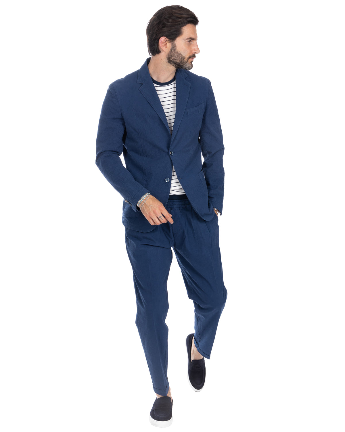 Navy blue textured linen-blend suit with relaxed fit trousers, striped tee, and black slip-on shoes. Smart casual menswear.