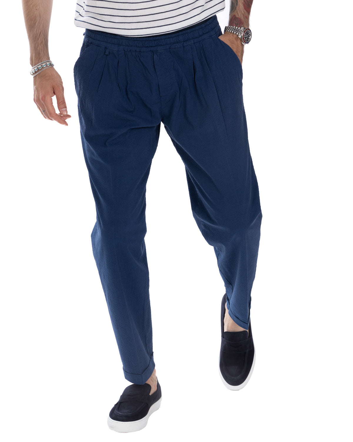 Navy blue pleated relaxed-fit trousers with elastic waist, cuffed hems. Lightweight woven fabric, casual men's pants.