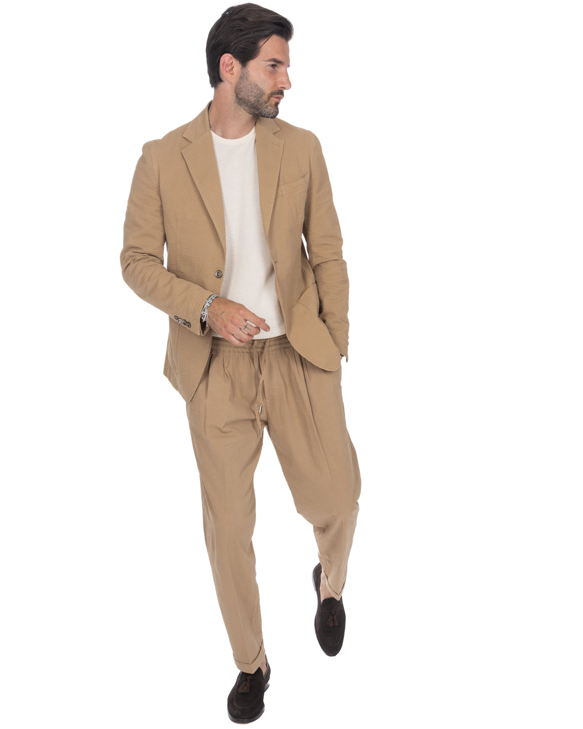 Men's beige seersucker suit with relaxed drawstring trousers, white knit tee, and black loafers.