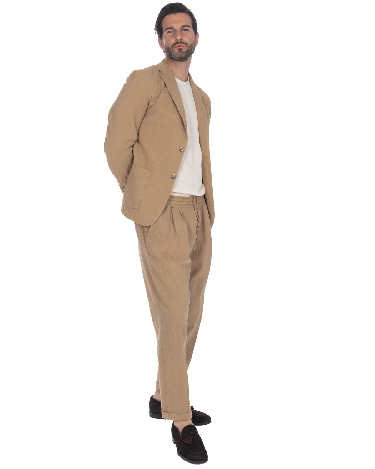 Men's beige seersucker suit with relaxed-fit drawstring pants, two-button blazer, and white knit tee.