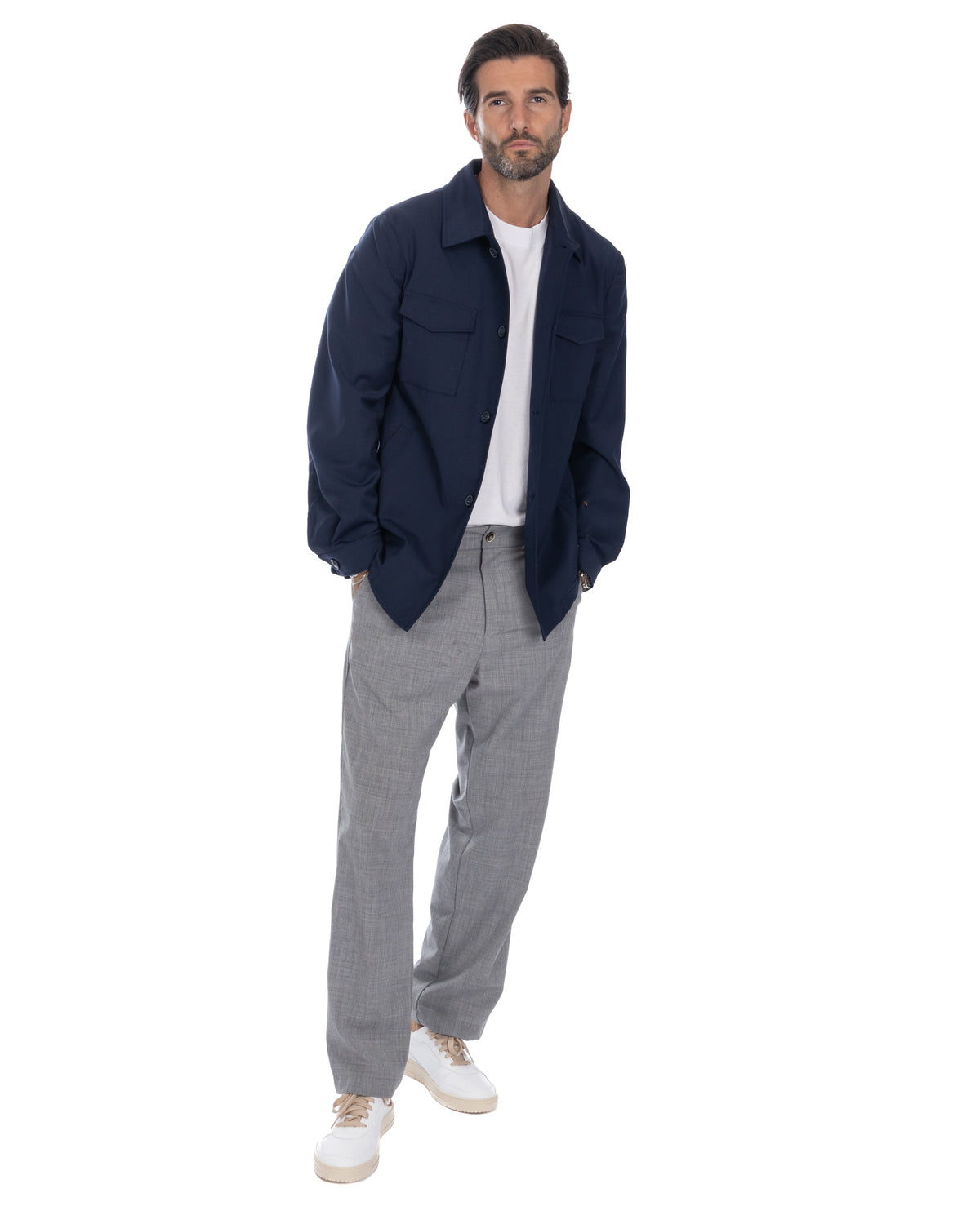 Navy wool overshirt jacket with white t-shirt, grey dress pants, and white sneakers. Men's smart casual outfit.