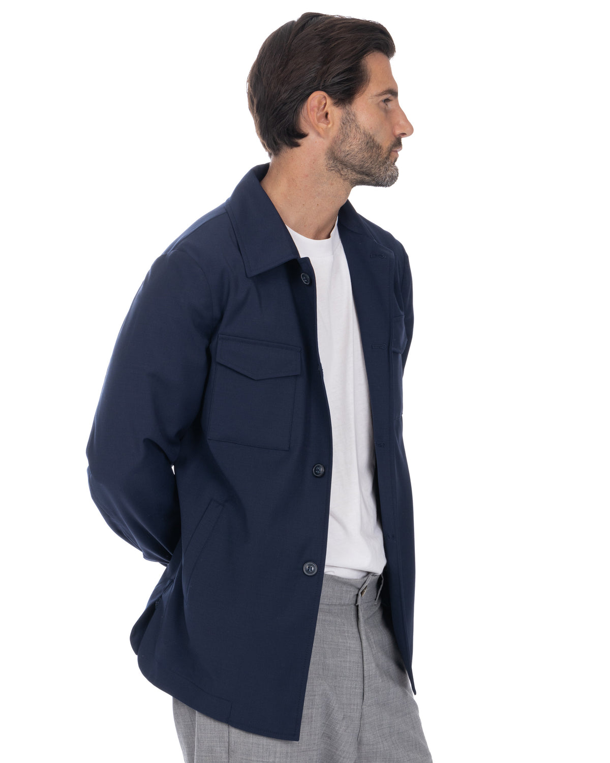 Navy blue button-up overshirt jacket with chest pocket, worn over white tee and gray trousers.