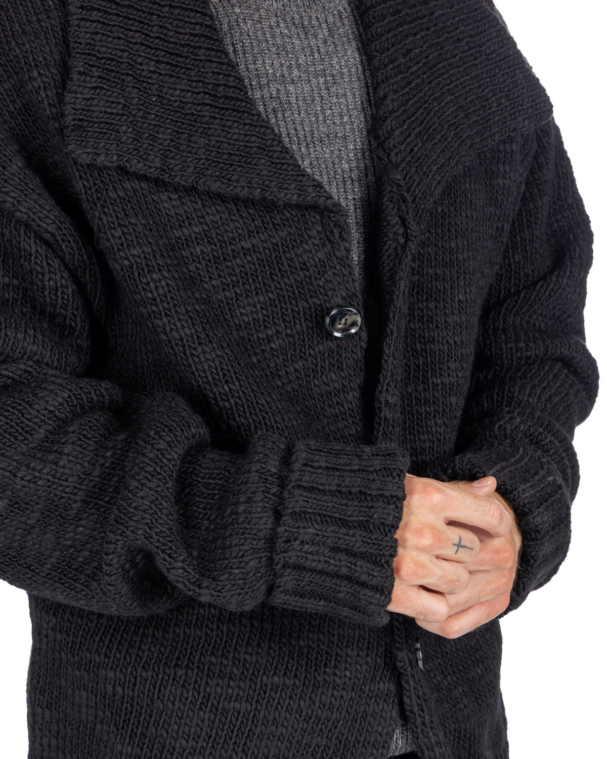 Black chunky knit cardigan sweater with button closure, textured wool blend fabric, worn over gray shirt