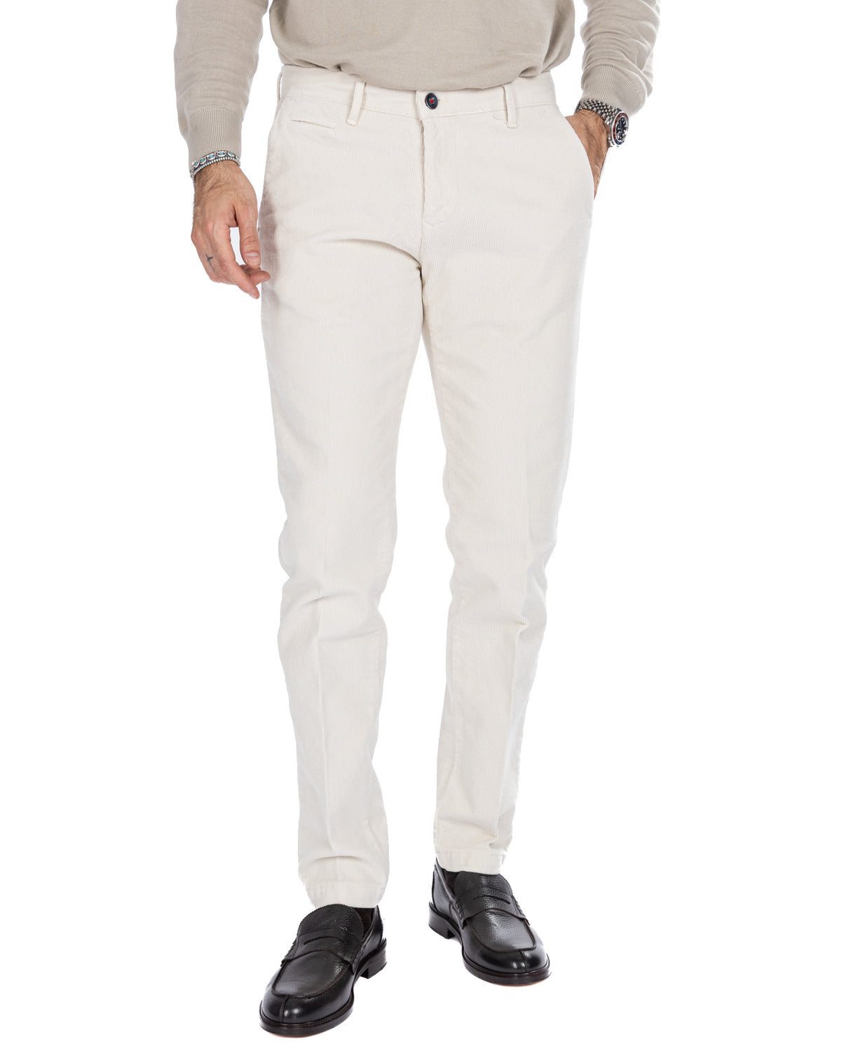 Men's white corduroy slim-fit trousers with button closure, paired with black leather loafers and beige sweater.