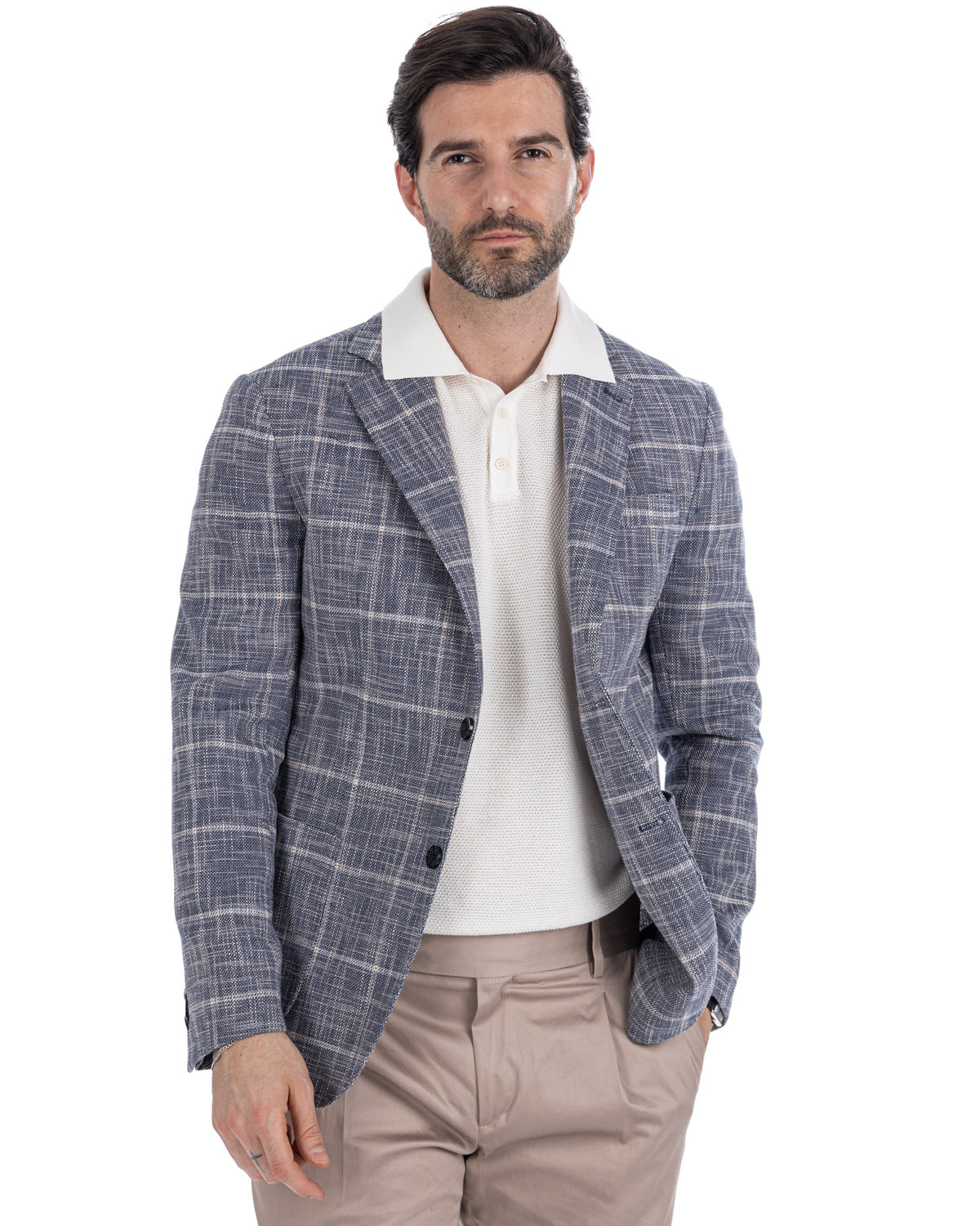Men's blue plaid linen blazer with white knit polo shirt and beige trousers, smart casual summer style.