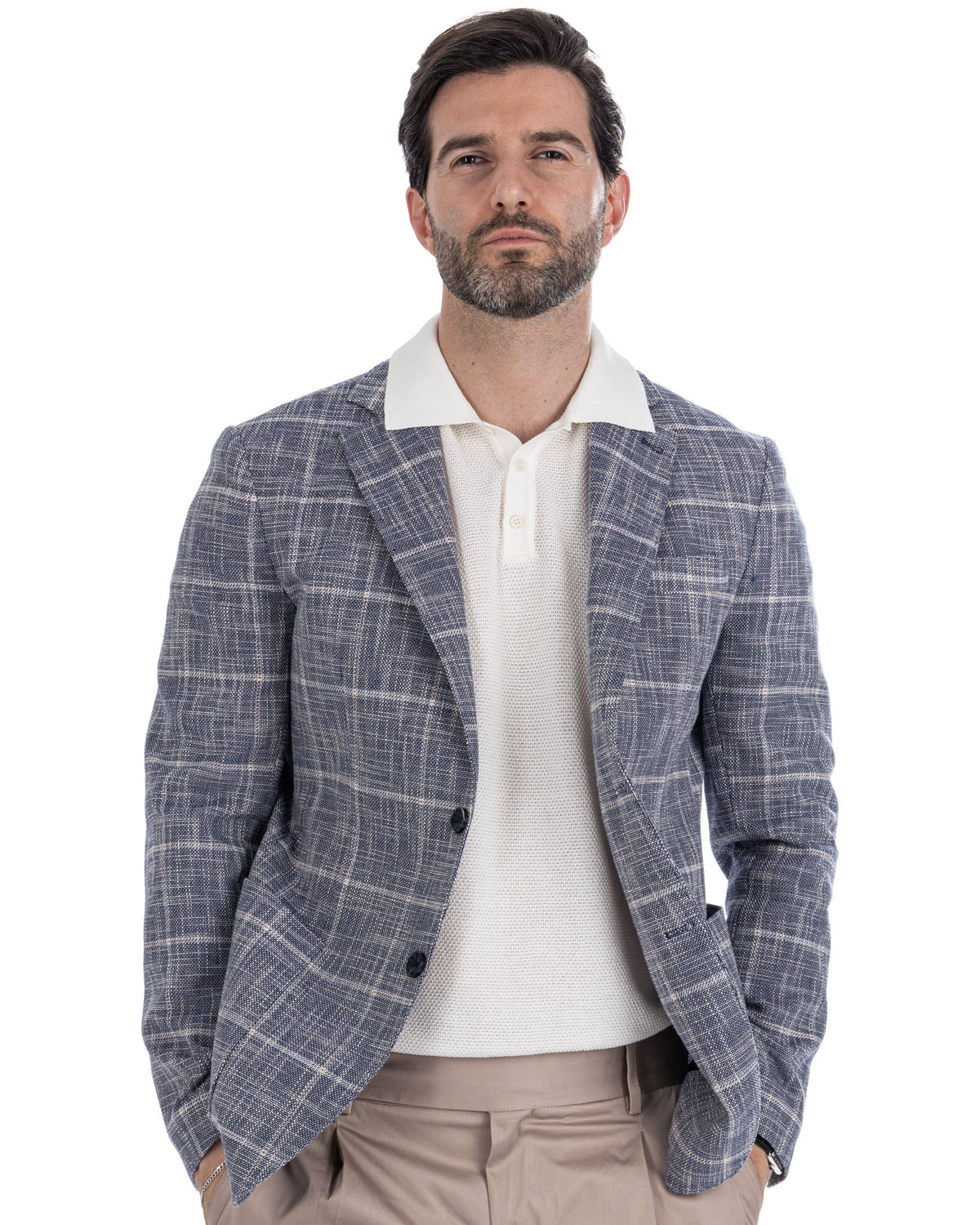 Men's blue plaid linen blazer with white knit polo shirt and beige trousers, smart casual summer style.