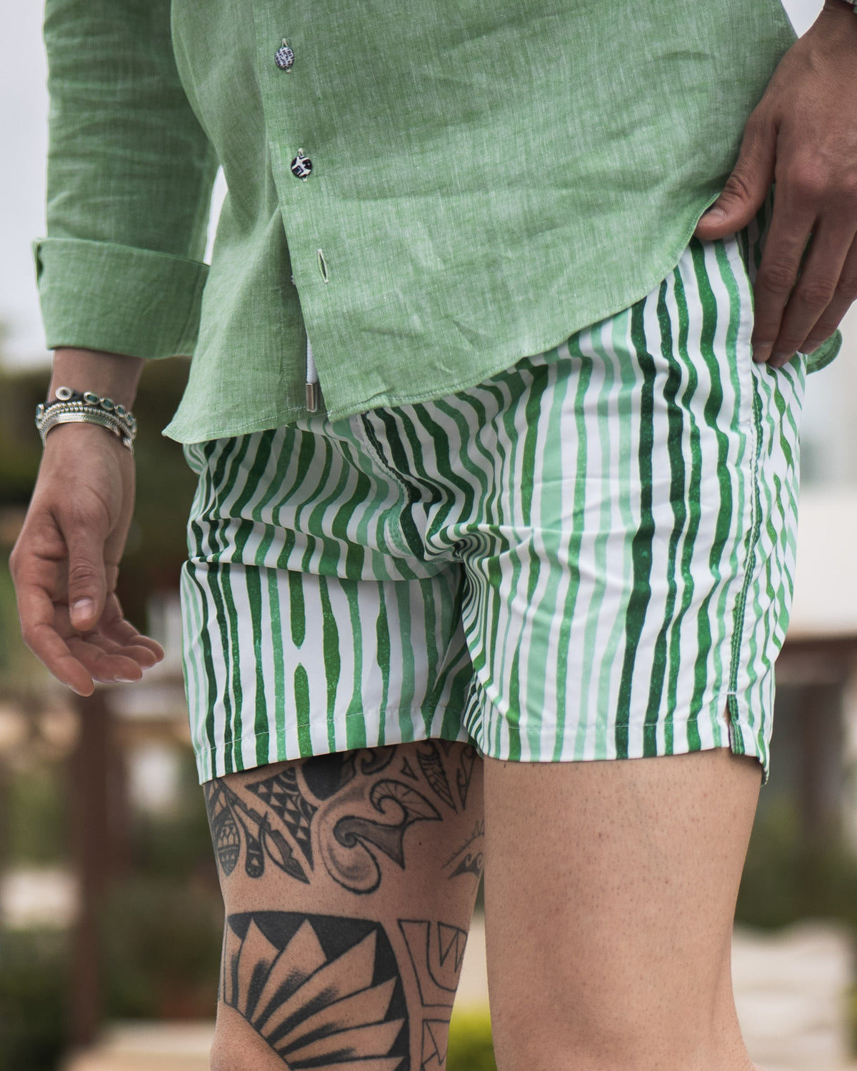 Green linen button-up shirt paired with green and white striped cotton shorts, casual summer menswear style.