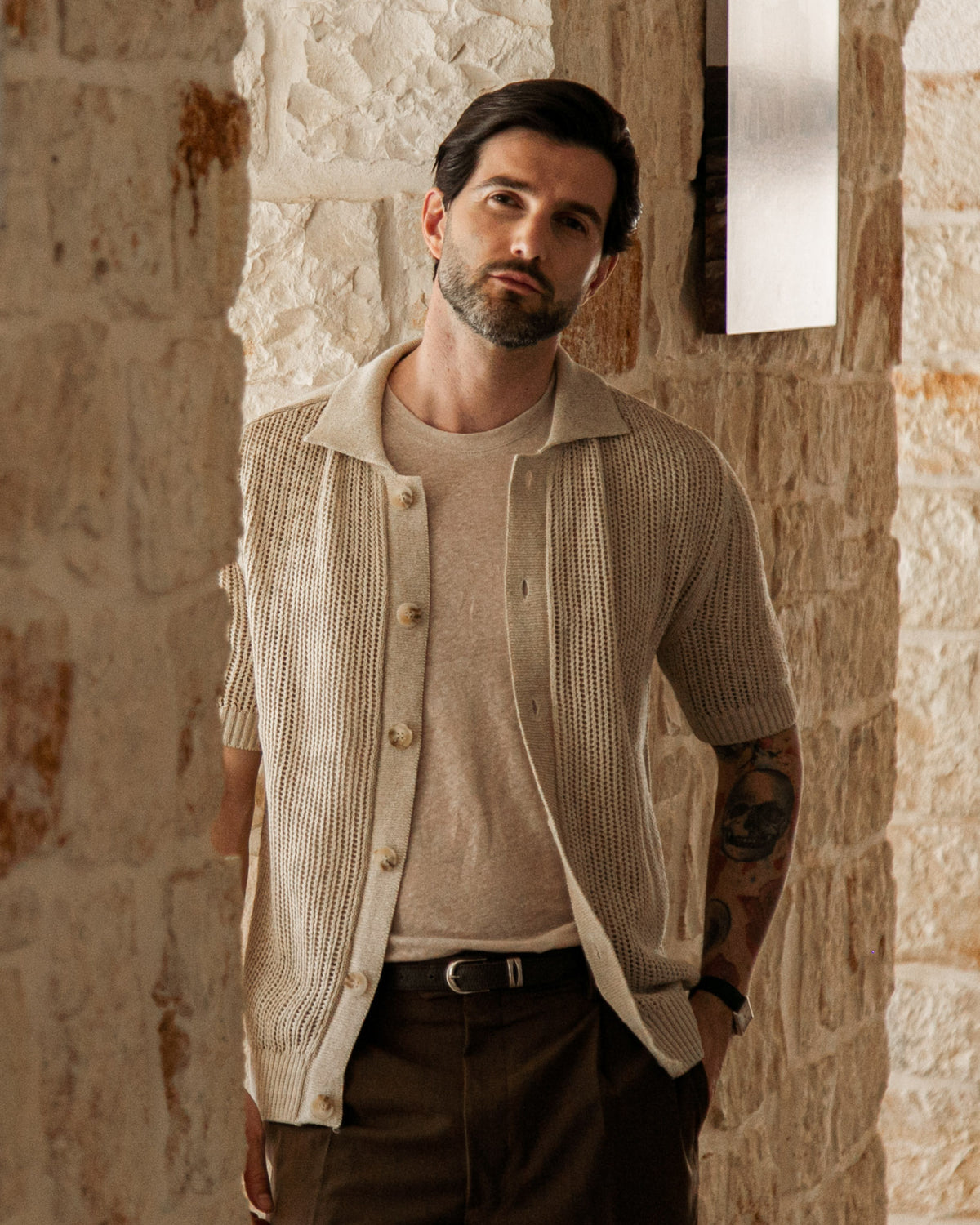 Beige short-sleeve knit cardigan with open weave texture, worn over tan tee and brown trousers.