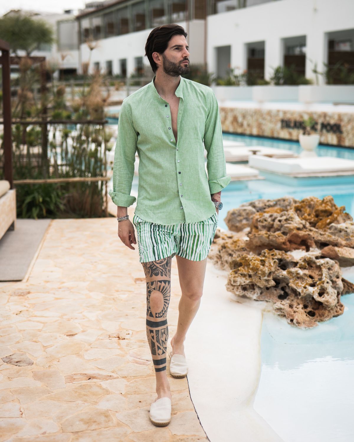 Light green linen button-up shirt with green striped shorts, summer resort wear for men, casual poolside fashion style.