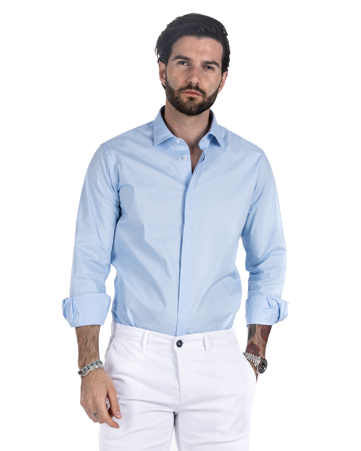Men's light blue cotton shirt with hidden placket and rolled cuffs, worn with white trousers, front view
