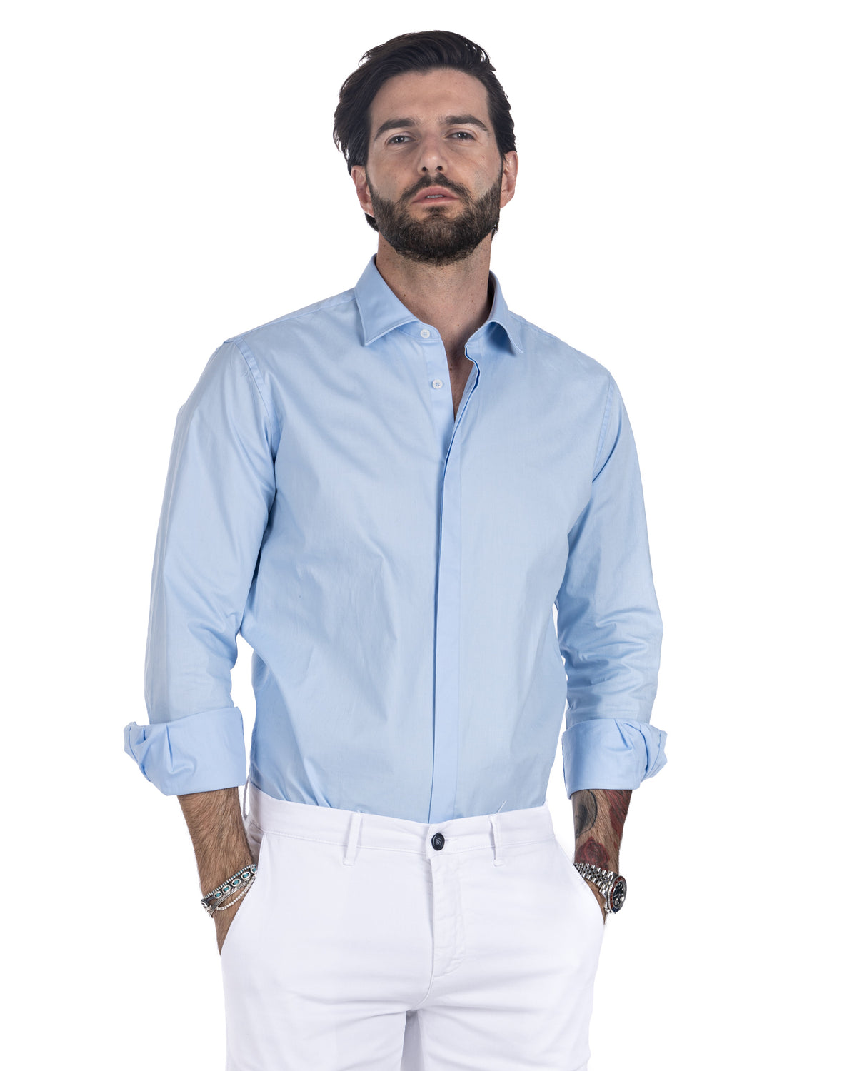 Men's light blue cotton shirt with spread collar, worn untucked over white trousers, front view