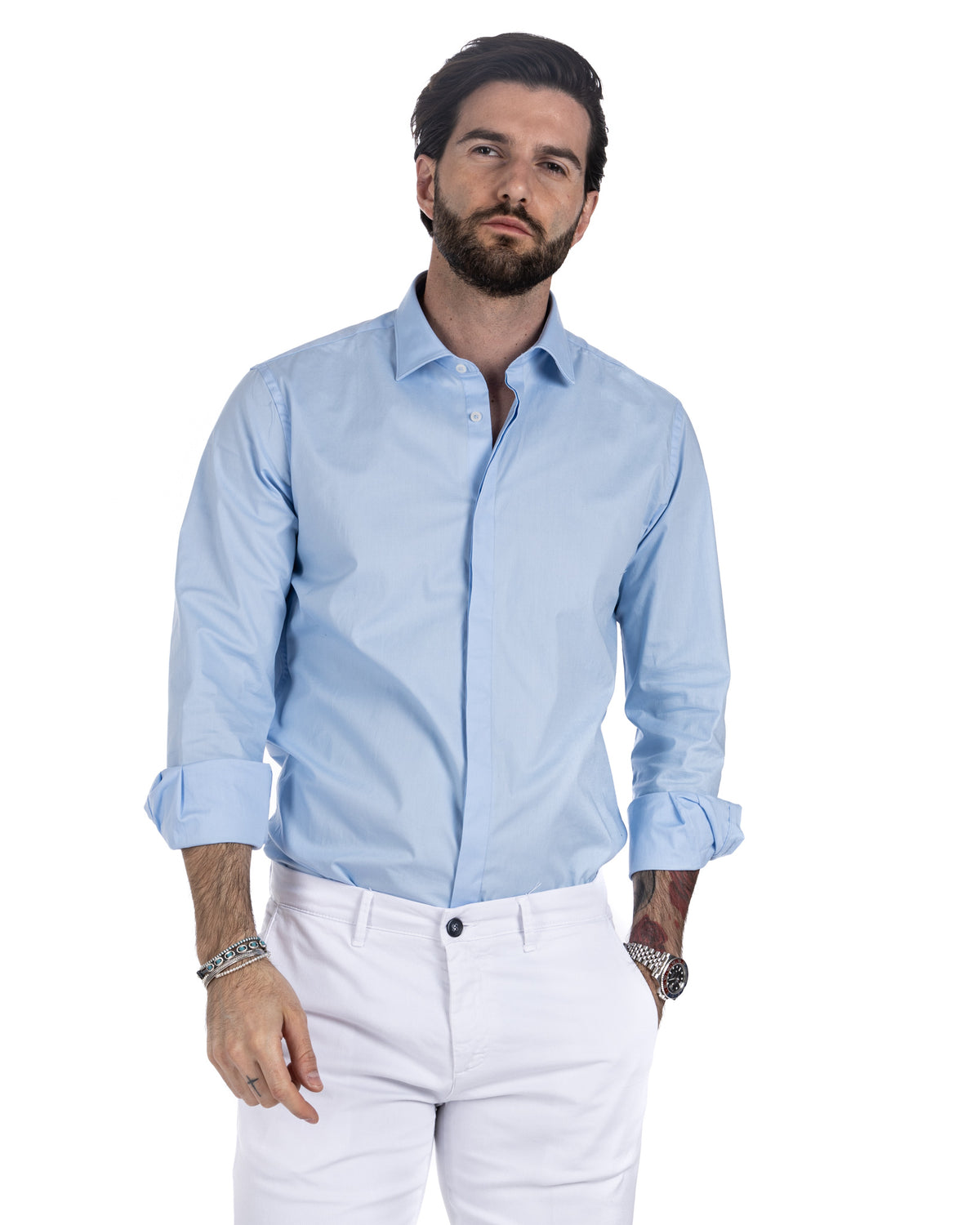 Men's light blue cotton shirt with rolled sleeves worn with white trousers and black loafers, front view