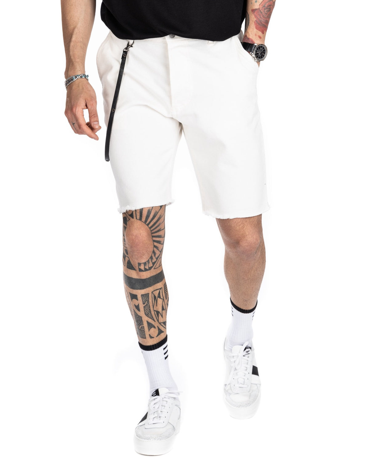 Men's off-white denim Bermuda shorts with raw-cut frayed hem, shown on a model walking