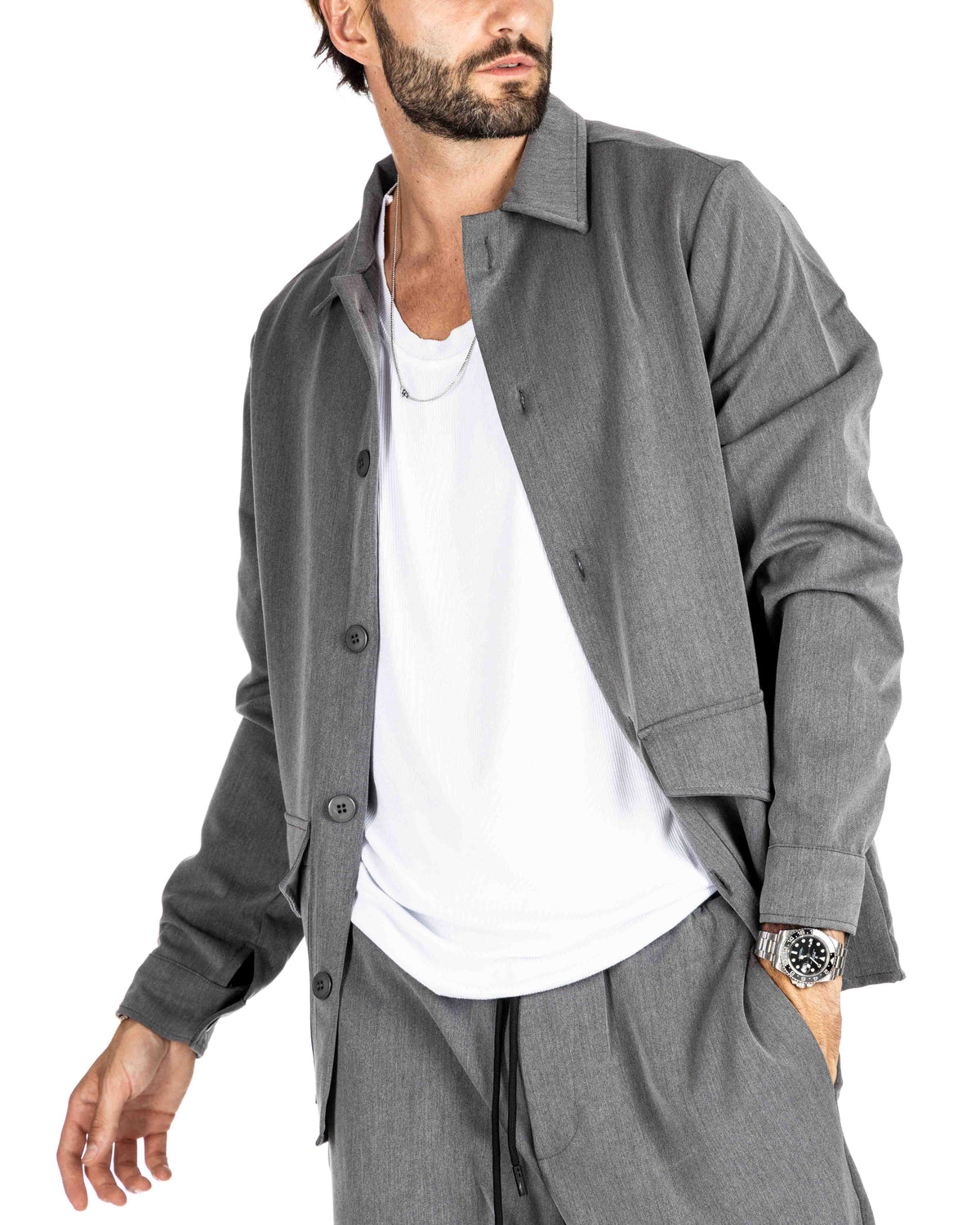 Men's gray knit overshirt with button-up front and patch pockets, worn with matching gray pants, shown on a model